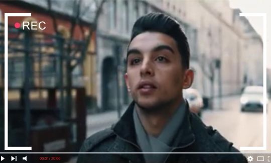 David Massa w szaliku i ciemnym płaszczu idzie ul. Piotrkowską. Wokół zdjęcia grafika imitująca kadr filmowy.