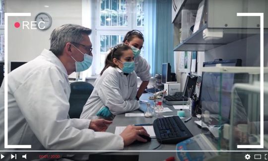 Trzech naukowców w białych fartuchach przy stole laboratoryjnym.