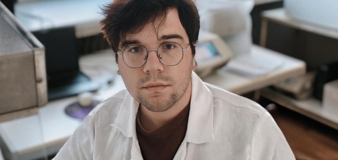 młody badacz w białym fartuchu i okularach siedzi w laboratorium