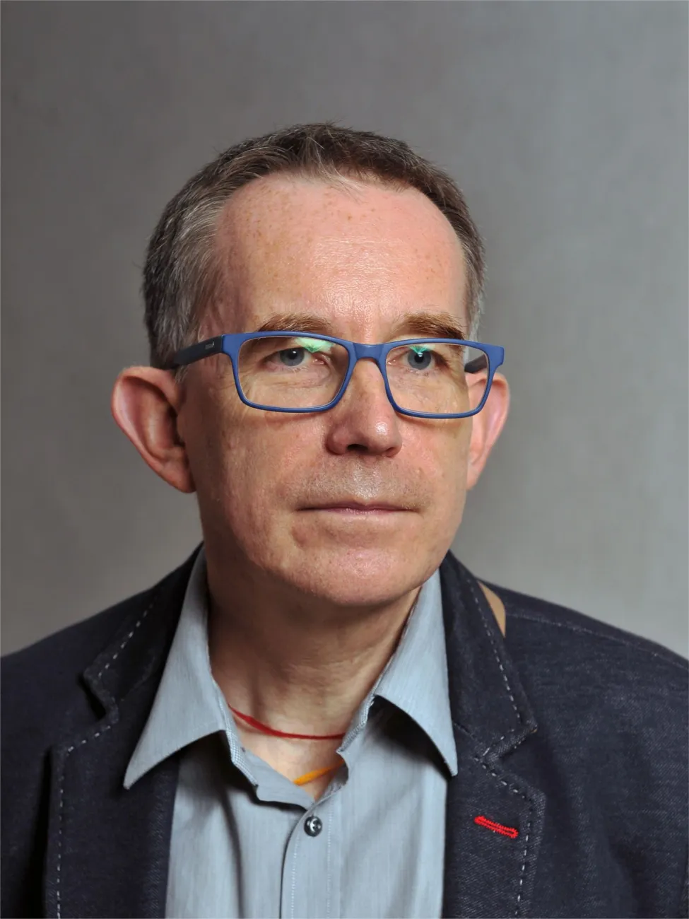 Portrait photo: Professor Michał Strzelecki wearing a dark jacket and a grey shirt against a grey background.