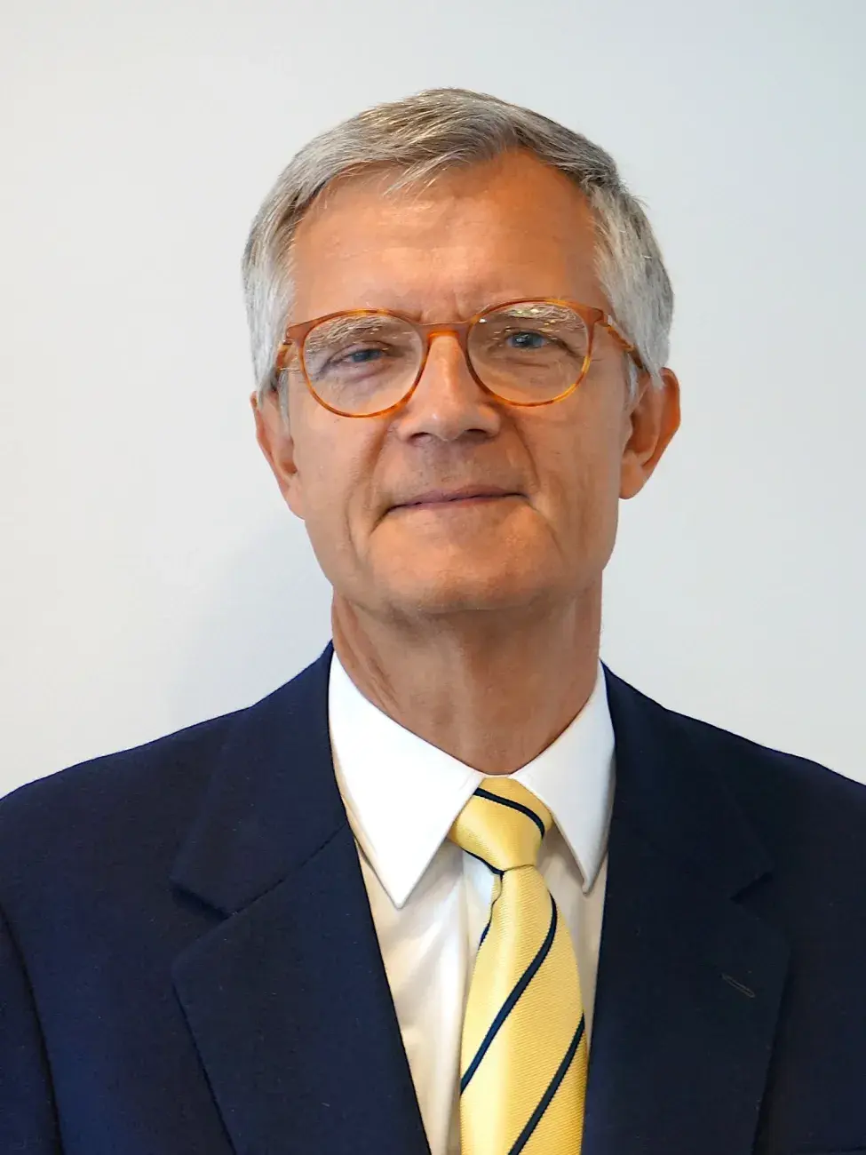 Zdjęcie portretowe: prof. Andrzej Bartoszewicz w czarnym garniturze i żółtym krawacie na jasnym tle.