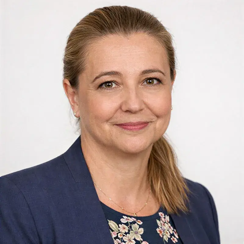 zdjecie legitymacyjne kobiety z włosmi blond związanymi, uśmiecha się, ma granatową marynarkę, tło białe