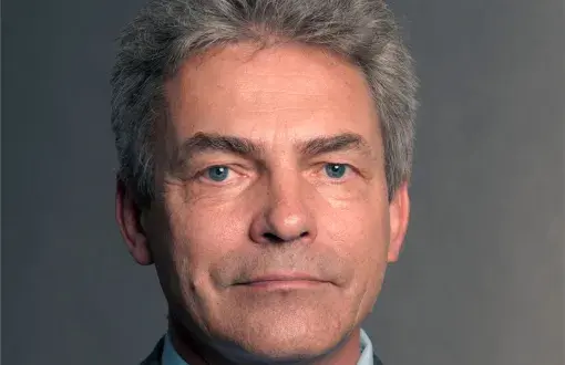 Zdjęcie portretowe: prof. Marek Lefik w ciemnej marynarce, niebieskiej koszuli i krawacie na szarym tle.