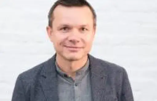 Zdjęcie portretowe: Sławomir Kierner w szarej koszuli i marynarce na białym tle.