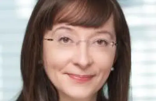 Zdjęcie portretowe: Marzena Wieczorkowska w ciemnej marynarce na rozmytym tle.