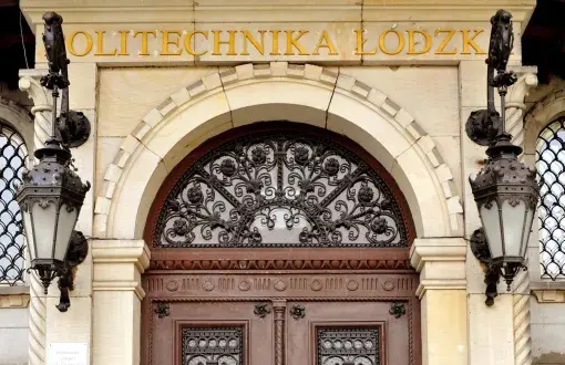 Fragment zabytkowego wejścia do Rektoratu PŁ.: drewniane drzwi, wiszące lampy.