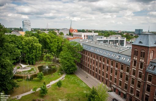 Kampus B z lotu ptaka: po lewej stronie zielone drzewa, po prawej stronie 4-kondygnacyjny, ceglany budynek Trzech Wydziałów.