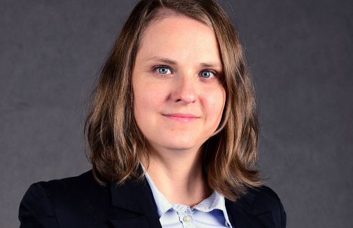 Zdjęcie portretowe: dr hab. inż. Marta Grumek, prof. PŁ w ciemnej marynarce i jasnej koszuli na szarym tle.