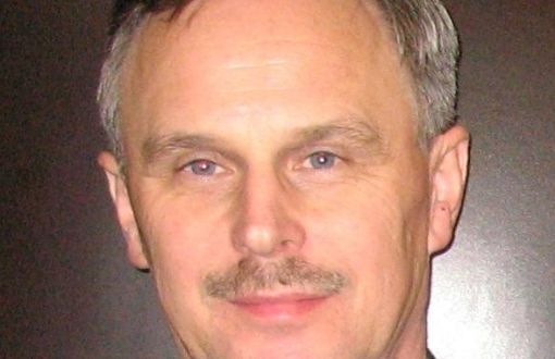 Zdjęcie portretowe: dr inż. Adam Rylski w czarnym garniturze i białej koszuli na szarym tle.