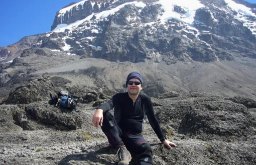 Prof. J. Banasiak ubrany w czarny sportowy strój na tle gór - masywu Uhuru Peak (Kilimandżaro).