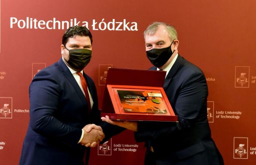 Rektor prof. Krzysztof Jóźwi0k odbiera gratulacje od prezesa Polskiej Agencji Przedsiębiorczości Wojciecha Pomarańskiego. Uścisk dłoni. JM Rektor trzyma pamiątkową tabliczkę w bordowym etui.