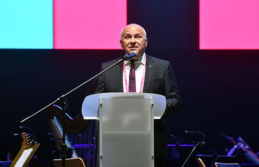 Adam Roczek stoi i przemawia przy mównicy.