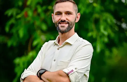 Zdjęcie portretowe: dr inż. Bartosz Sekuła na tle zieleni.
