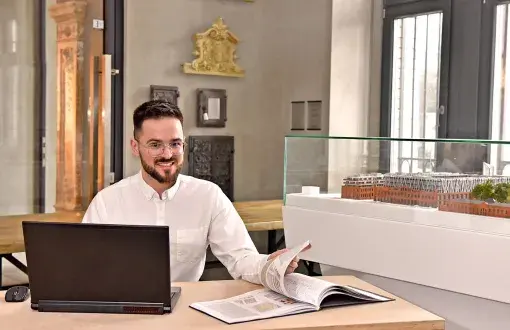 Jakub Misiak siedzi przy biurku w nowoczesnym biurze.