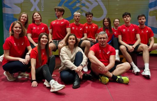 Drużyna na medal, sportowcy w czerwonych koszulkach z trenerką