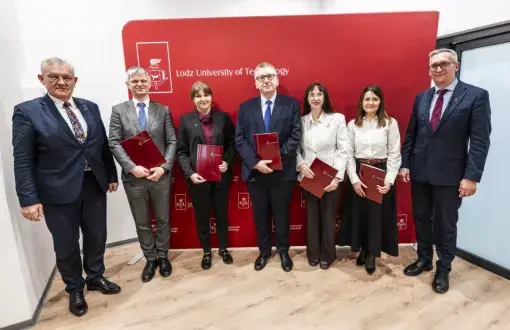 Laureatki i laureaci stypendium profesorskiego trzymają teczki w rękach, obok stoją dwaj mężczyni w garniturach