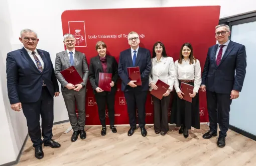 Laureatki i laureaci stypendium profesorskiego trzymają teczki w rękach, obok stoją dwaj mężczyni w garniturach