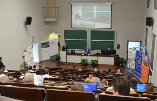 zdjęcie auli wypełnionej słuchaczami, na przed katedrą przemamia mężczyna w garniturze