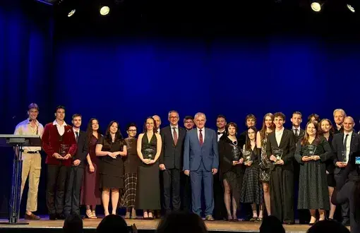 Grupa osób na scenie pozująca z nagrodami